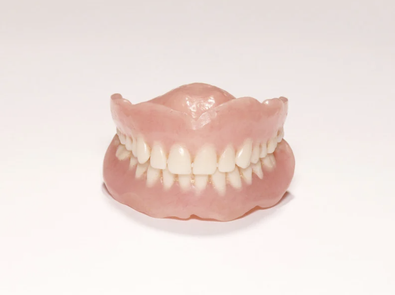 Personne tenant un dentier provisoire dans sa main.